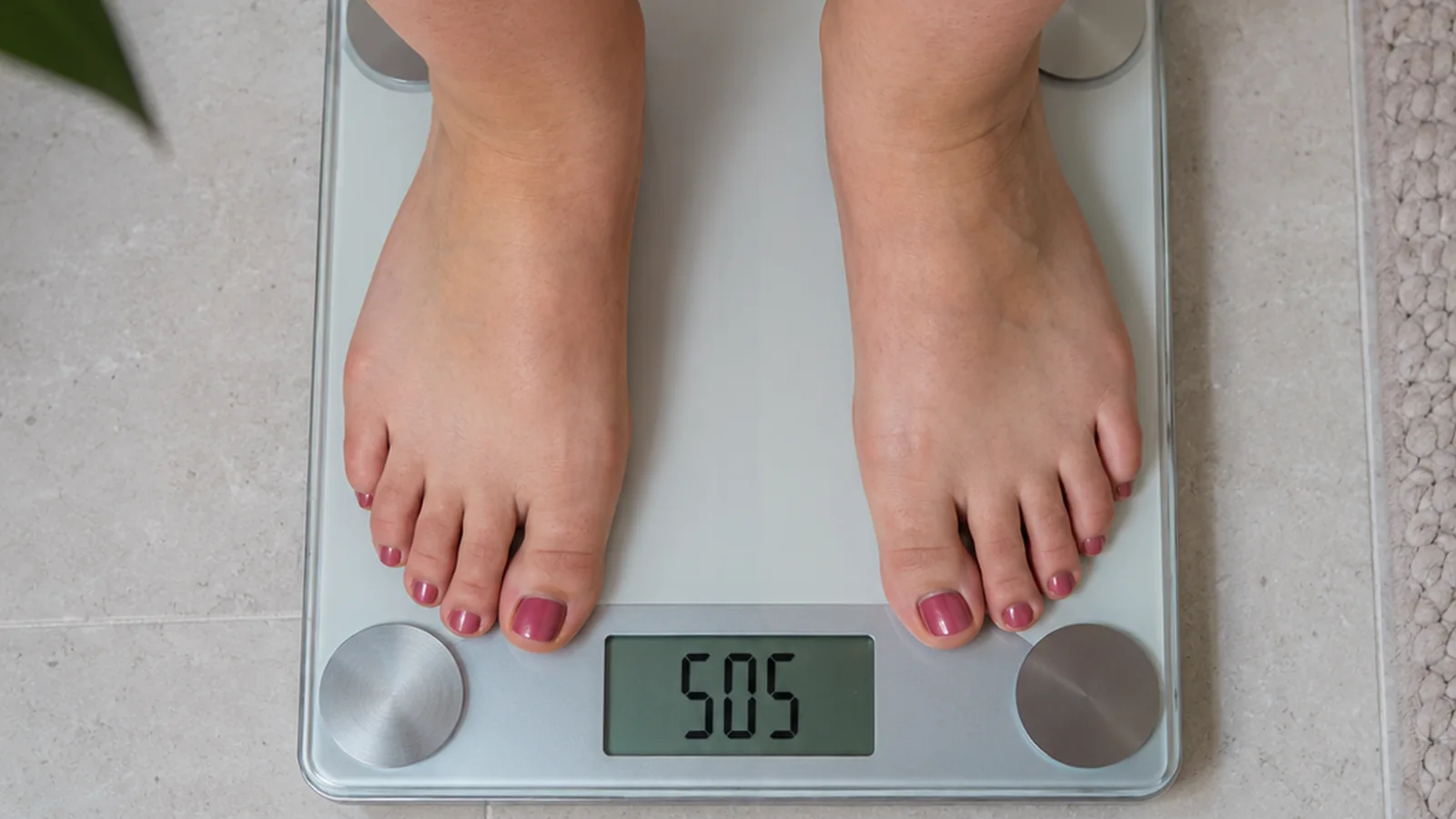 Pieds d’une femme sur une balance numérique dont l’écran affiche « SOS » à la place du poids